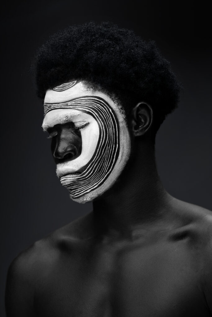 Conceptual portrait of a person with intricate white and black painted patterns on their face