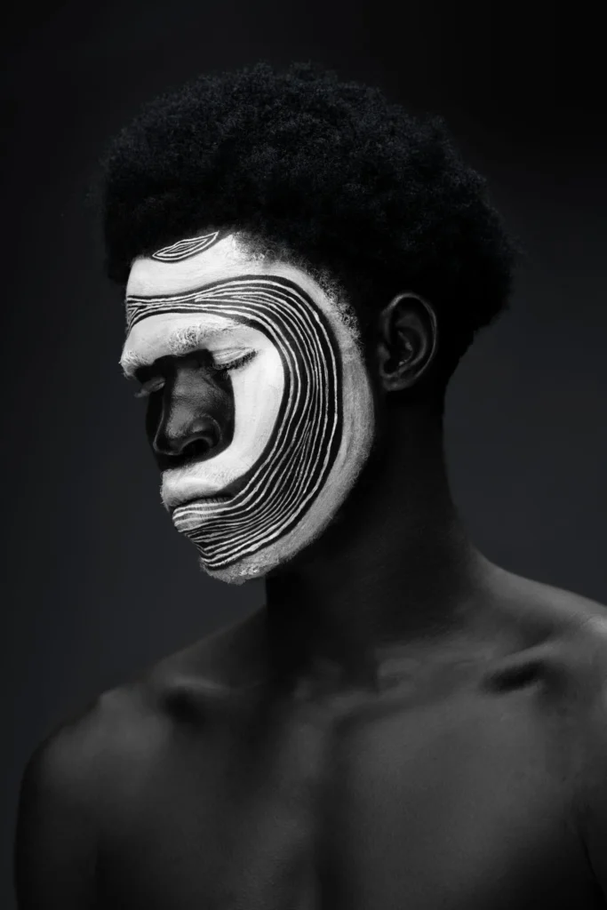 Conceptual portrait of a person with intricate white and black painted patterns on their face