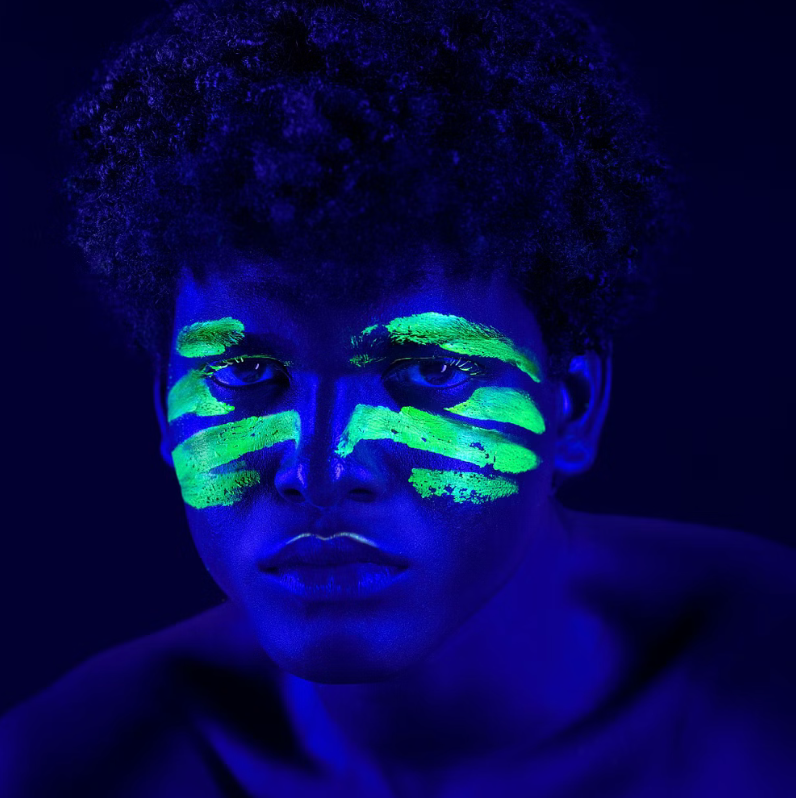 Portrait with glowing neon green face paint under UV light.