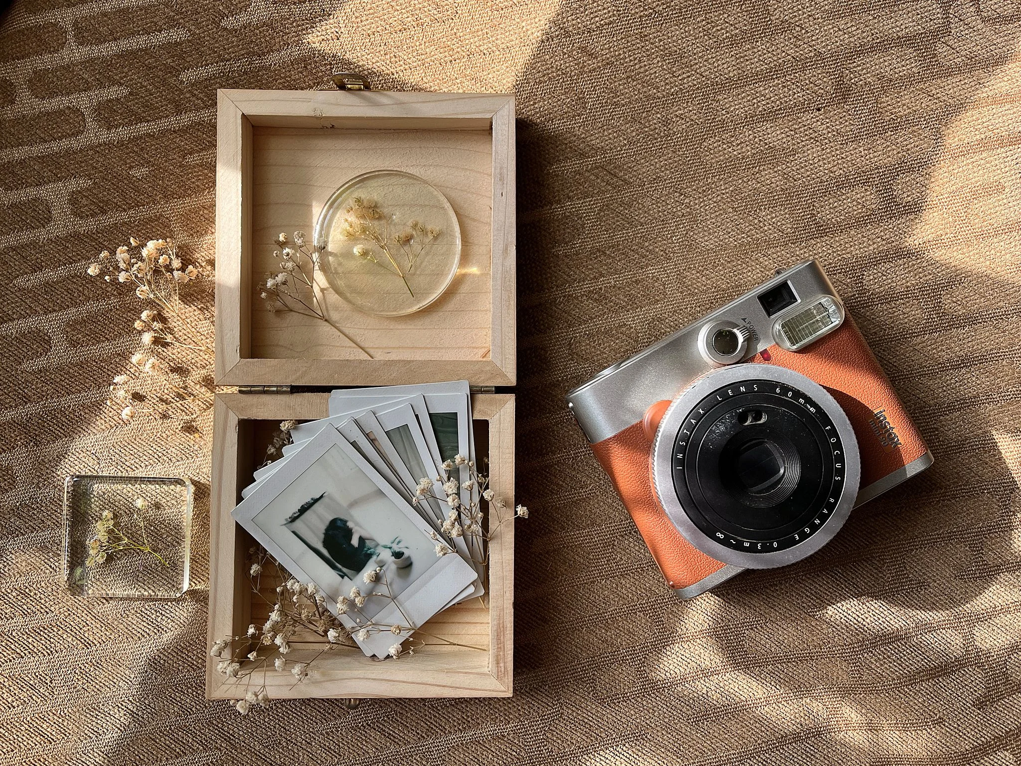 Vintage instant camera with wooden boxes of polaroids and dried flowers.