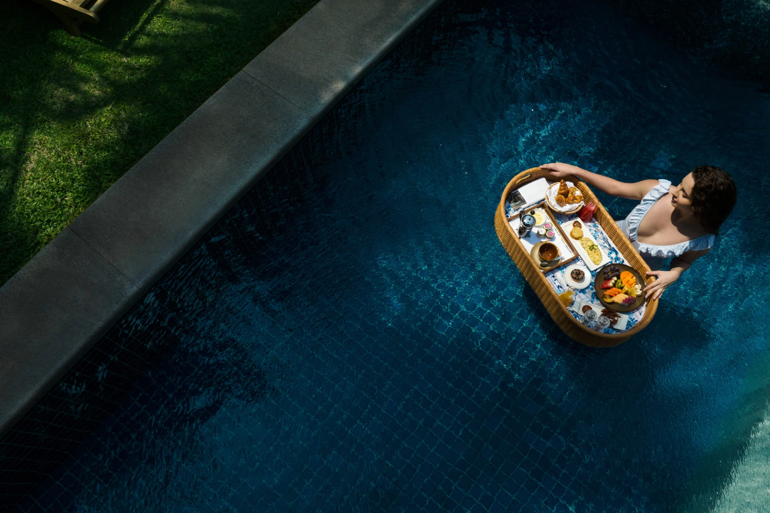 Woman enjoying a floating breakfast in a pool.