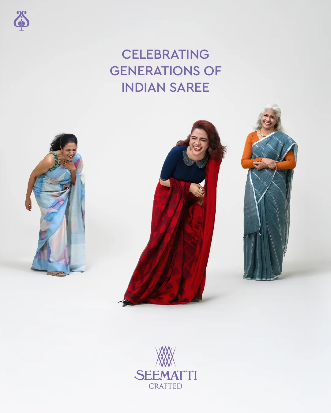 Three women across different age groups are captured mid-laughter, dressed in handwoven sarees in shades of pastel blue, deep red, and teal. They stand against a plain white studio backdrop under the campaign title "Celebrating Generations of Indian Saree." Their body language is natural and candid, emphasizing joy, intergenerational connection, and the emotional warmth tied to traditional Indian textiles. The logo “Seematti Crafted” is placed below, highlighting the brand’s focus on handcrafted elegance.