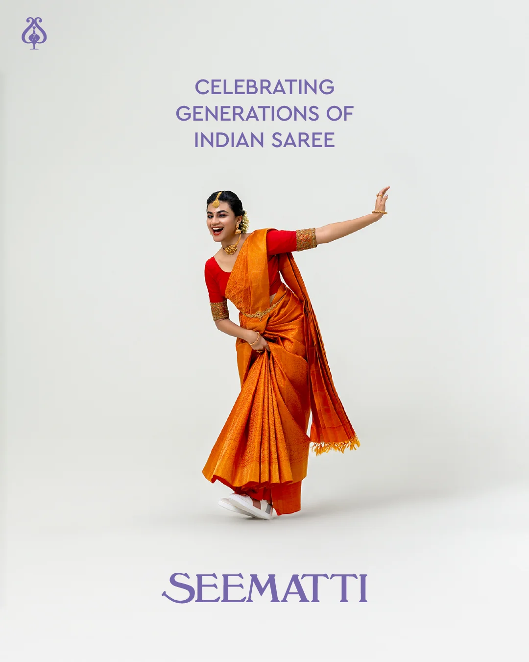 Woman dancing joyfully in a traditional orange saree.