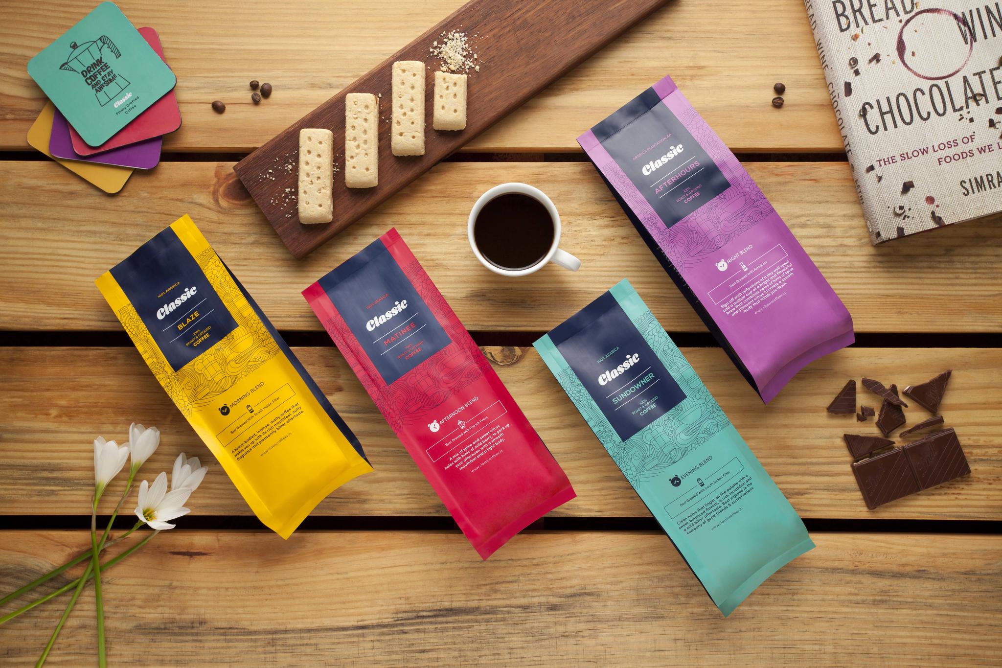 Colorful premium coffee packs styled with snacks, chocolate, and a fresh cup of brew.
