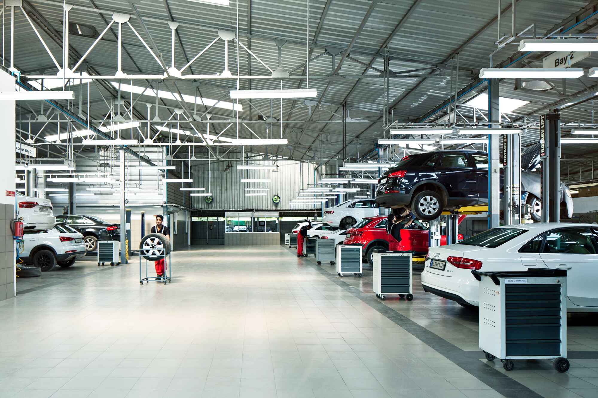 Modern car service center with vehicles on lifts and mechanics at work.