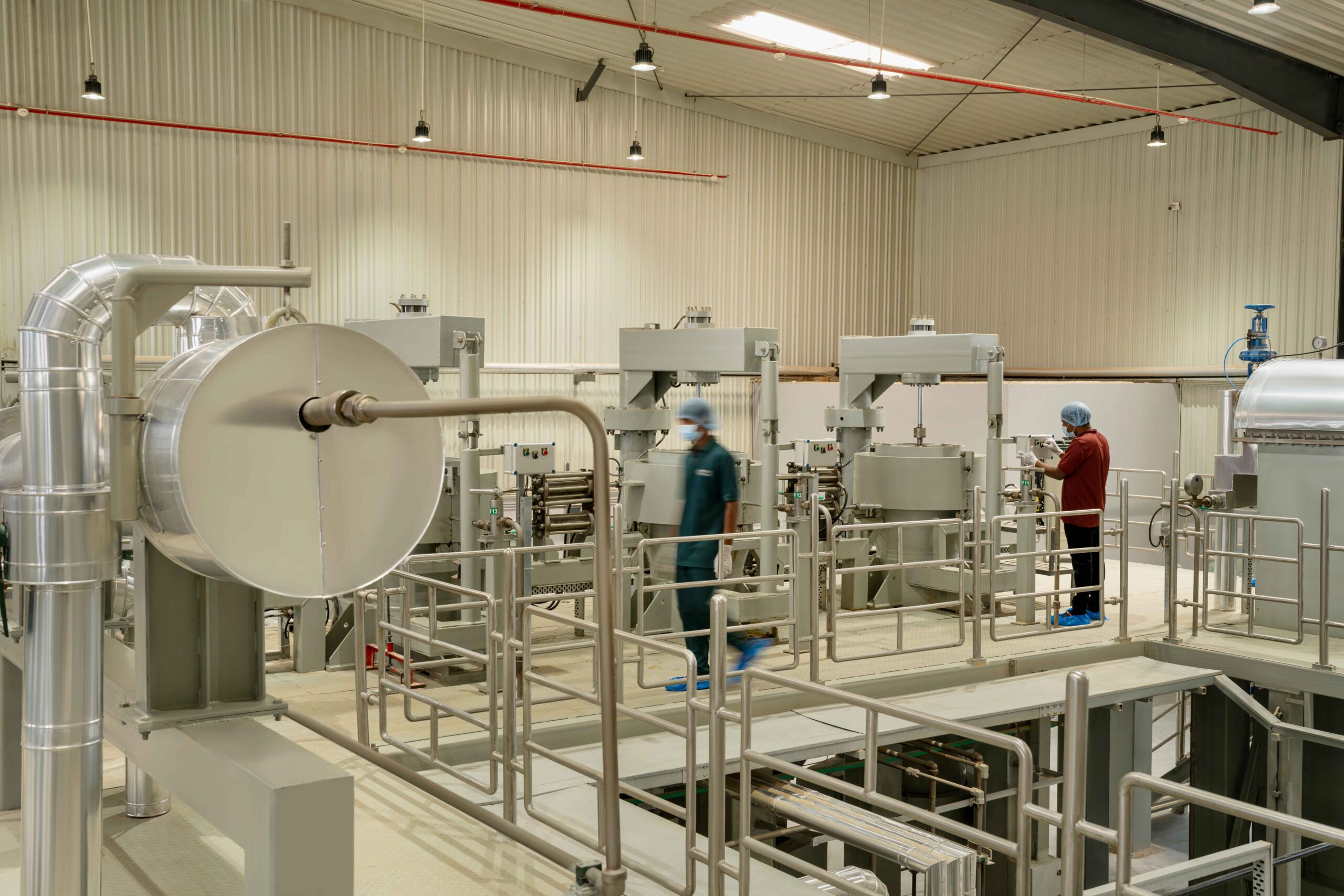 Industrial food processing plant with automated machinery and workers in safety gear.