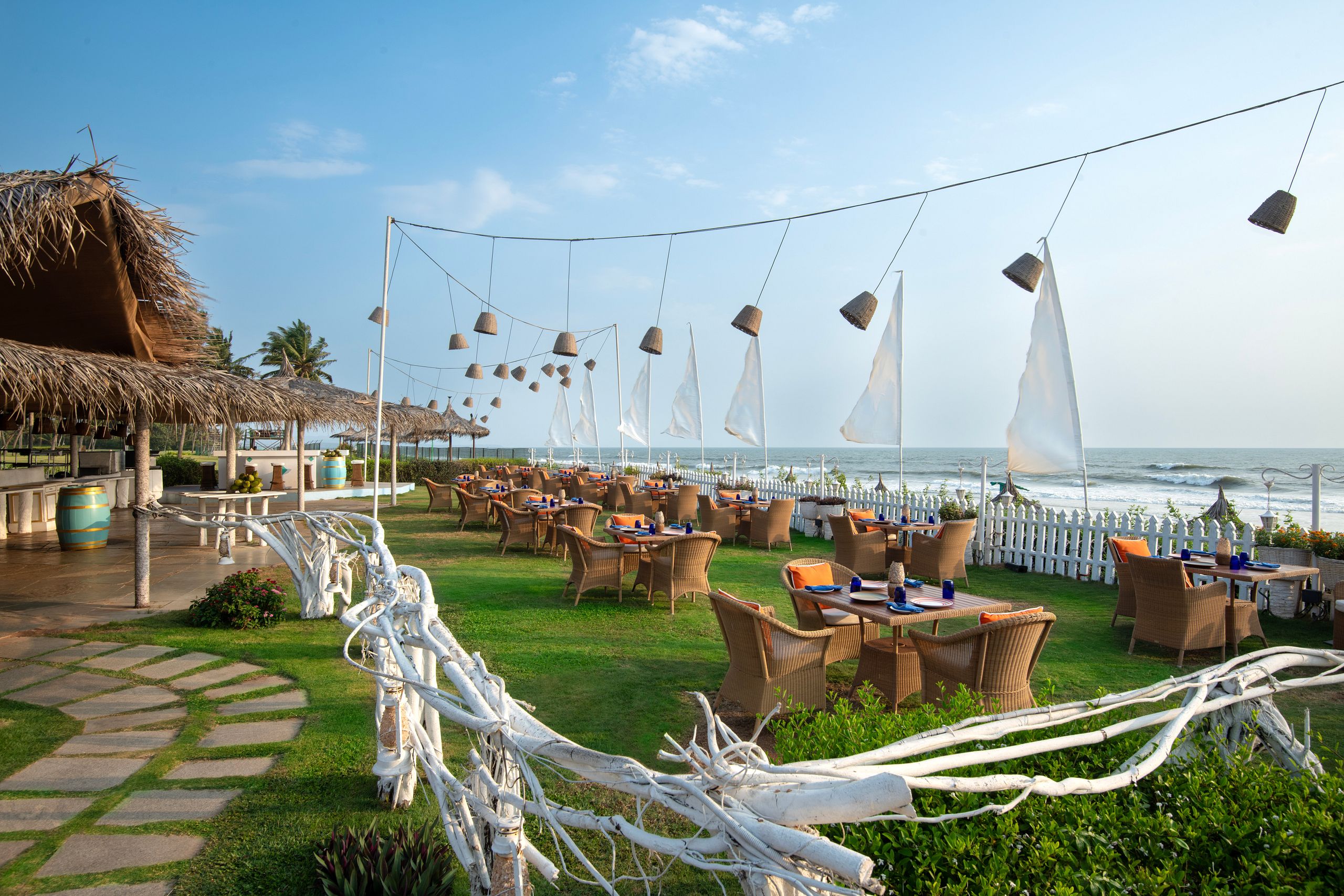 Beachfront outdoor dining area with wicker seating and ocean views.